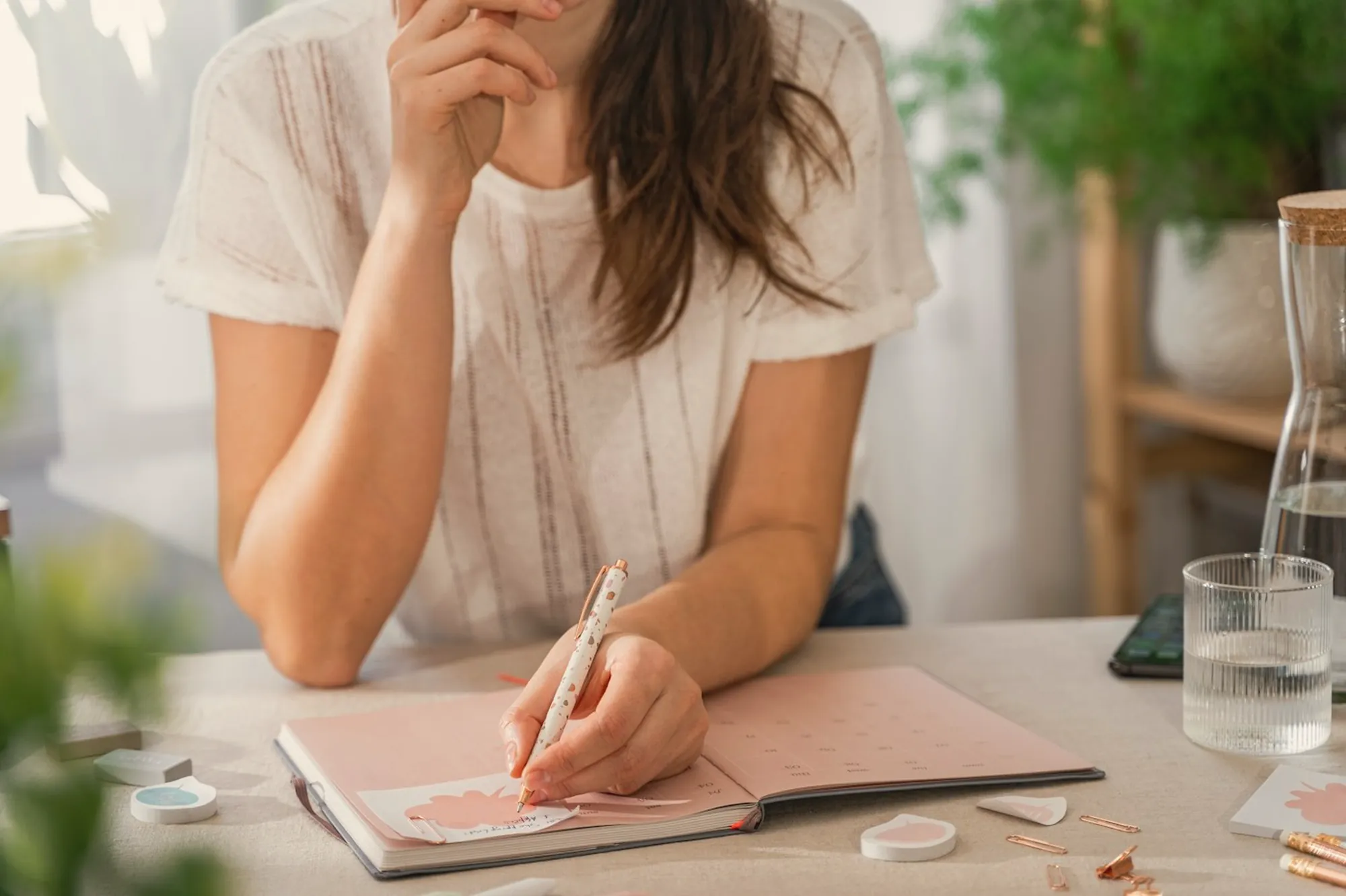A woman thinks over her notes at a desk